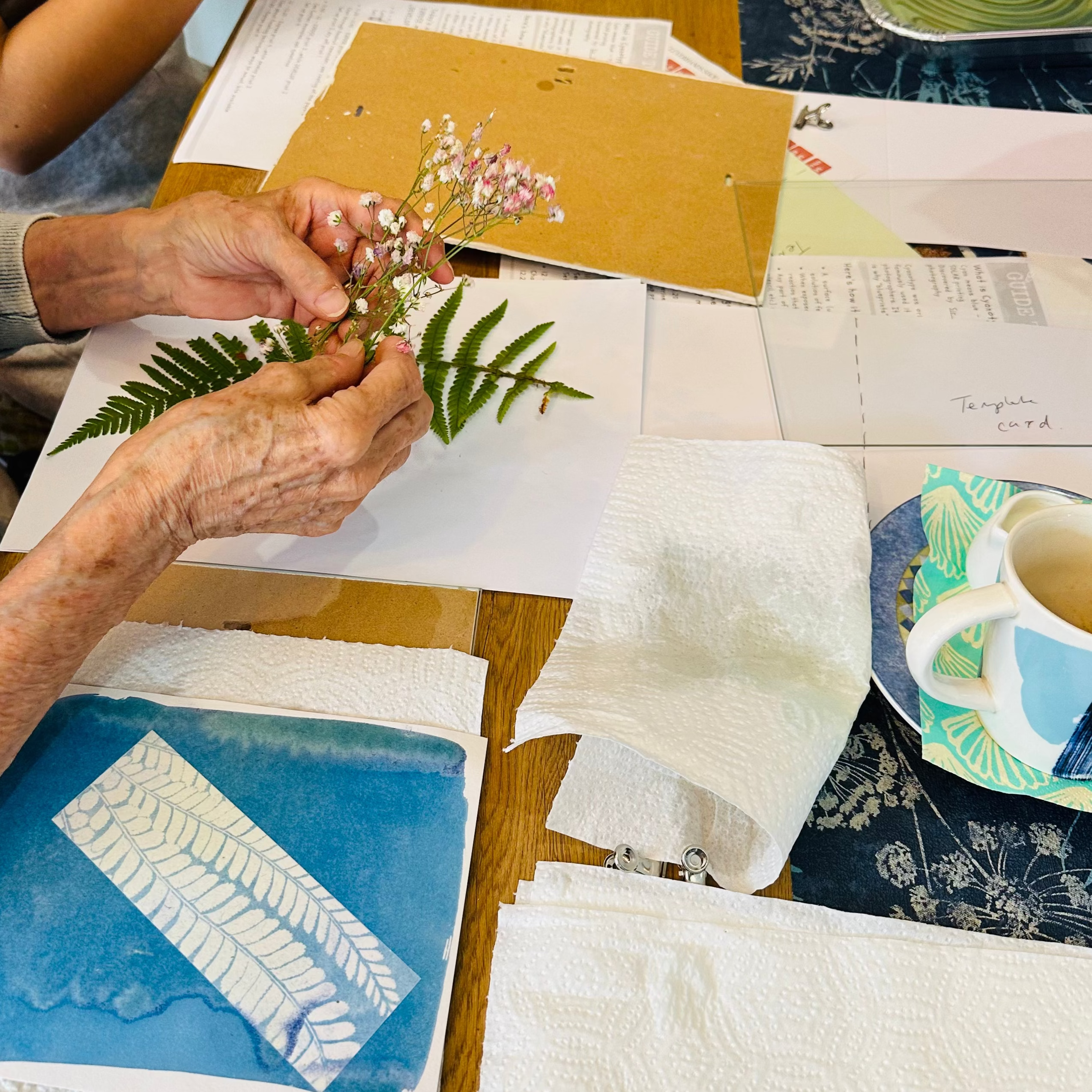Two people working on a craft project with materials on a table.