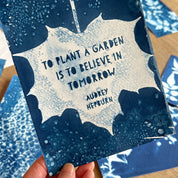 Blue card with a quote by Audrey Hepburn held by a hand, with more cards in the background.