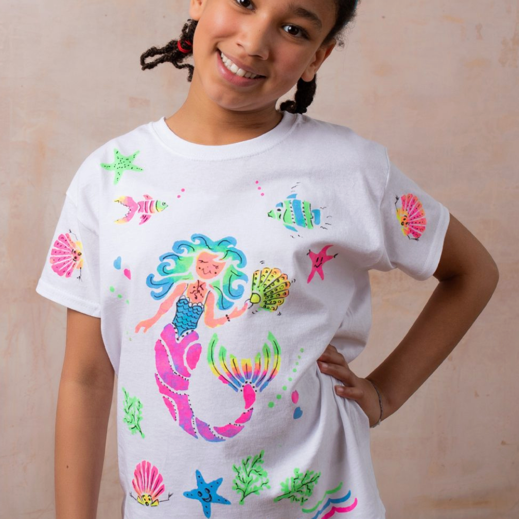 Child wearing a white t-shirt with colorful mermaid design on a beige background