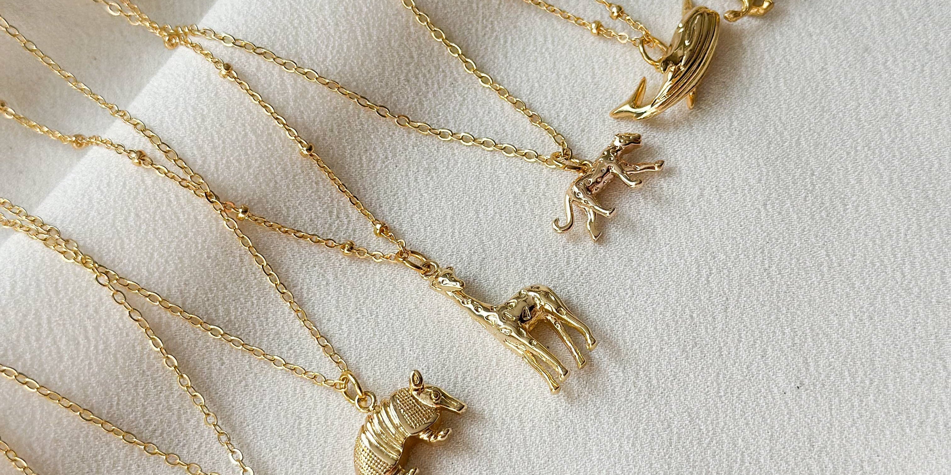 Gold necklaces with various pendants on a light background