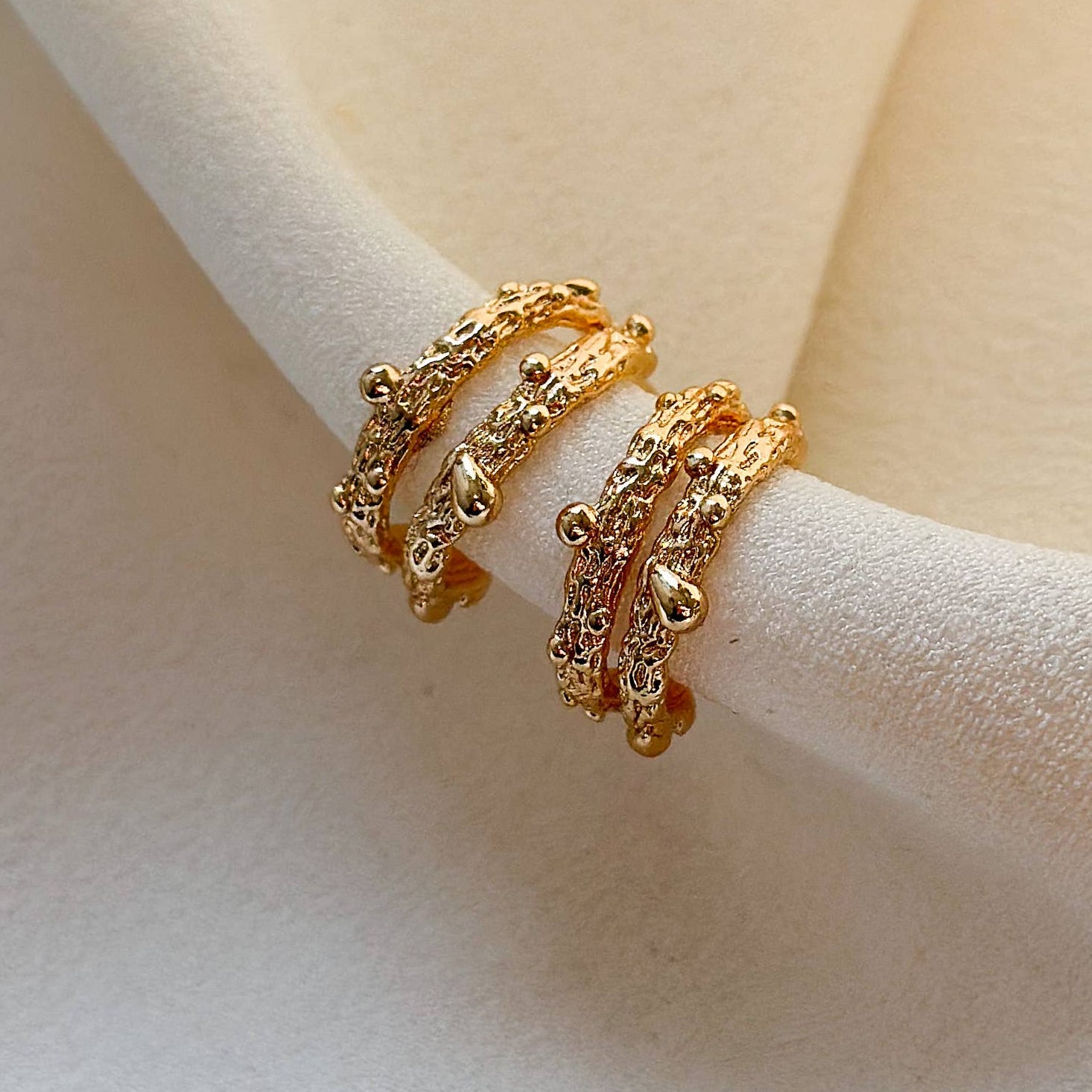 Gold ring on a white stand against a beige background