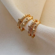 Gold ring on a white stand against a beige background