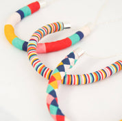 Three colorful fabric-covered hoop necklaces with silver-toned metal caps and chains, arranged on a plain white background.