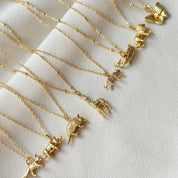 Gold necklaces with various pendants on a light background