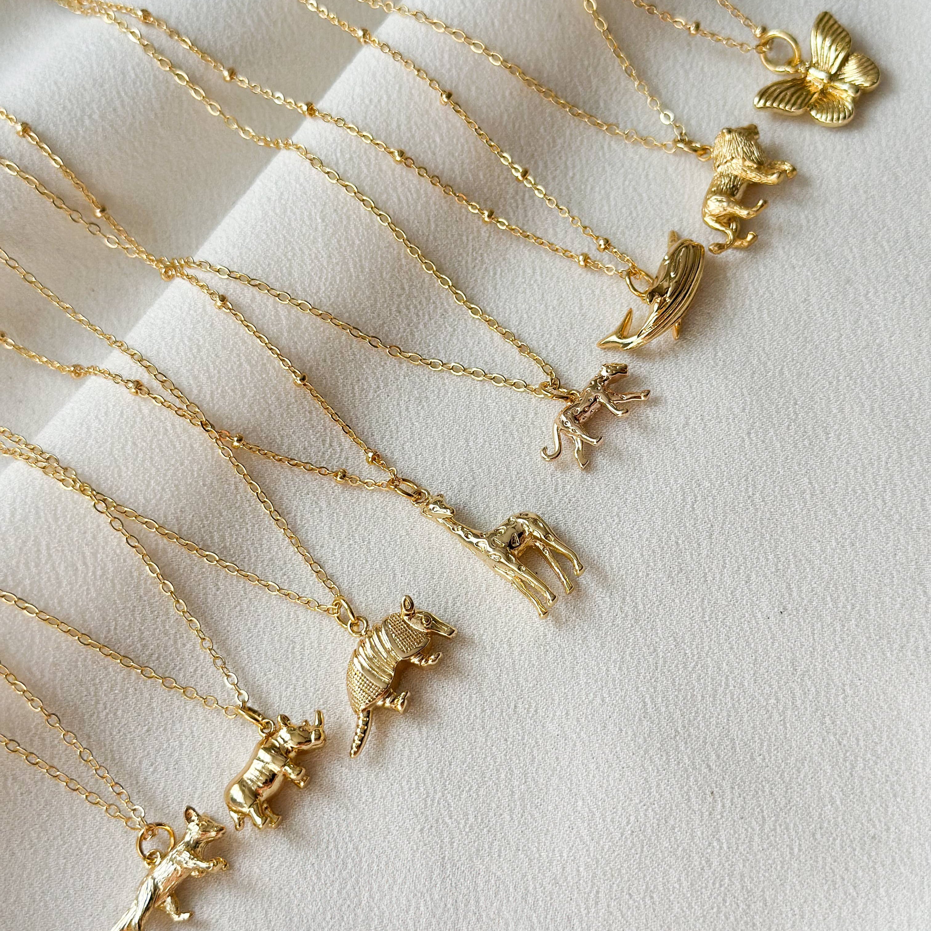Gold necklaces with various pendants on a light background