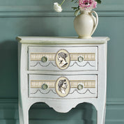 Vintage-style side table with decorative knobs against a teal wall