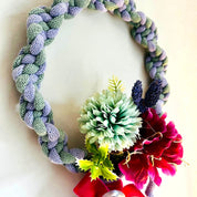Decorative wreath with braided rope, flowers, and ribbons on a white background