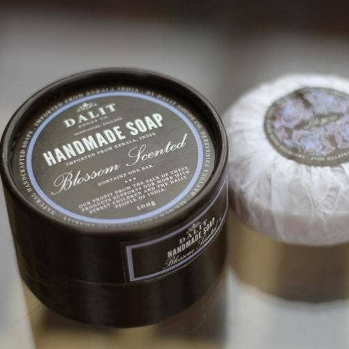 Handmade soap in a black container with a white soap bar on a reflective surface