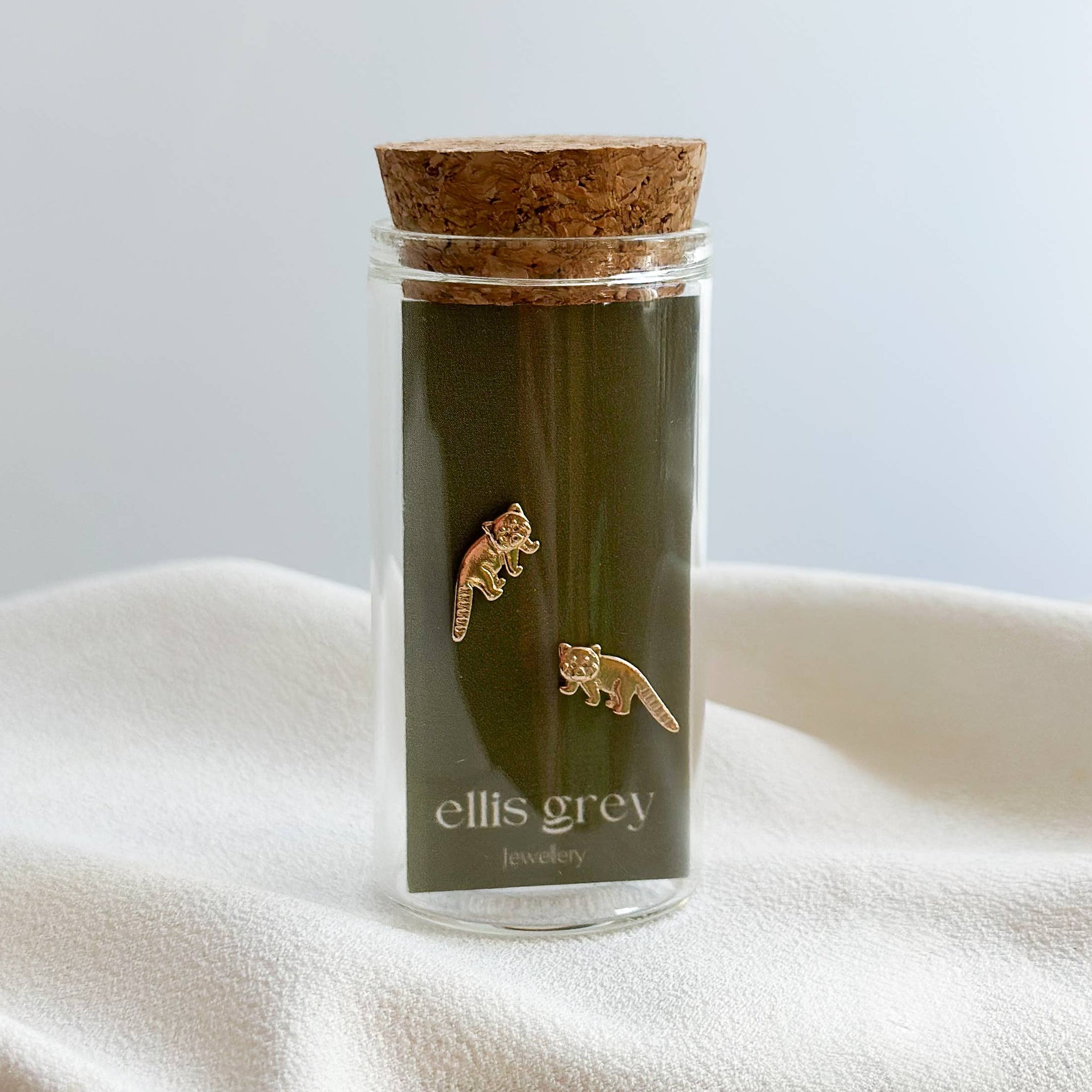 Glass jar with cork lid containing green tea, branded 'ellis grey', on a white surface.