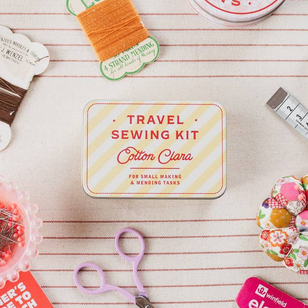 Travel sewing kit with various sewing supplies on a wooden surface