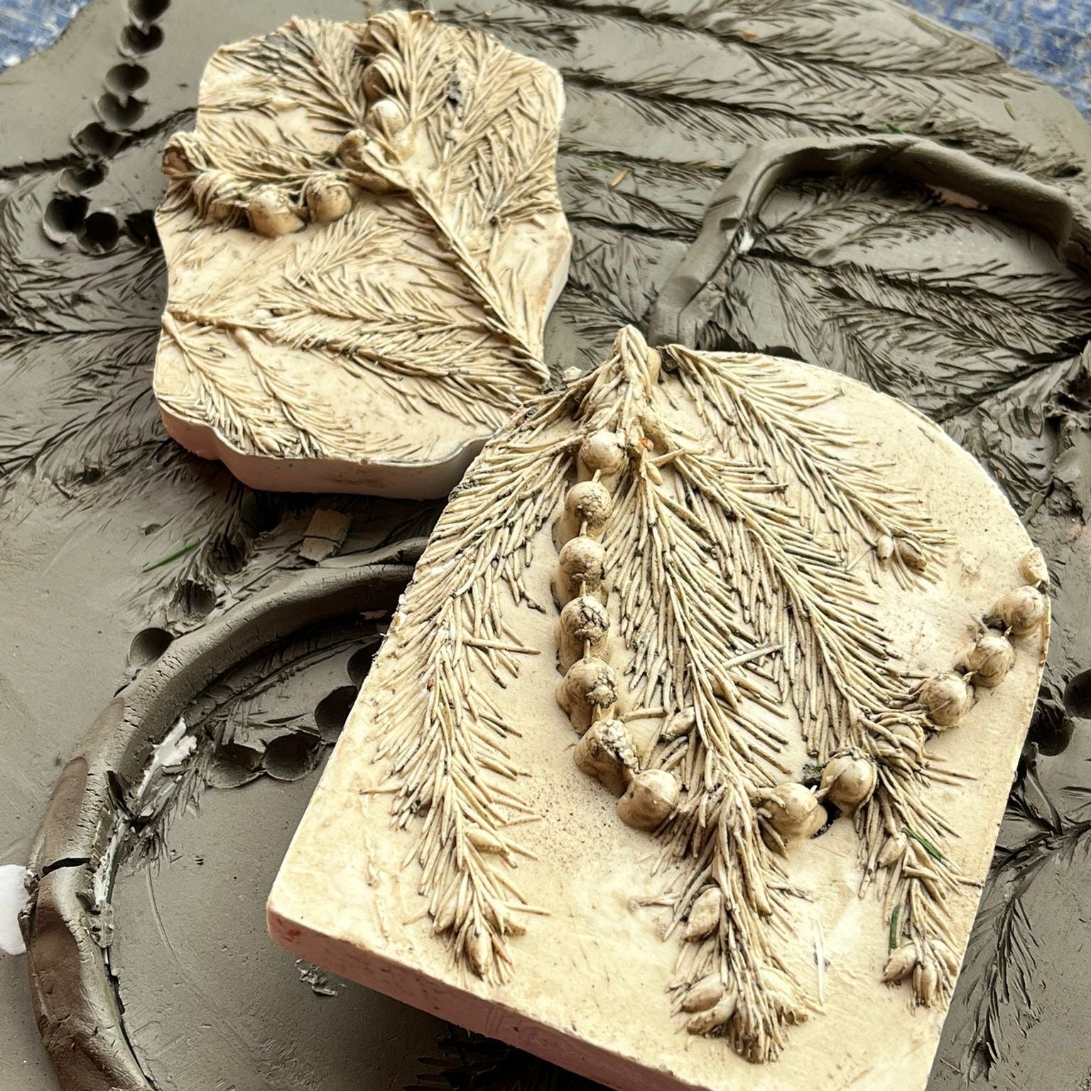 Clay mold with leaf and berry design on a textured surface