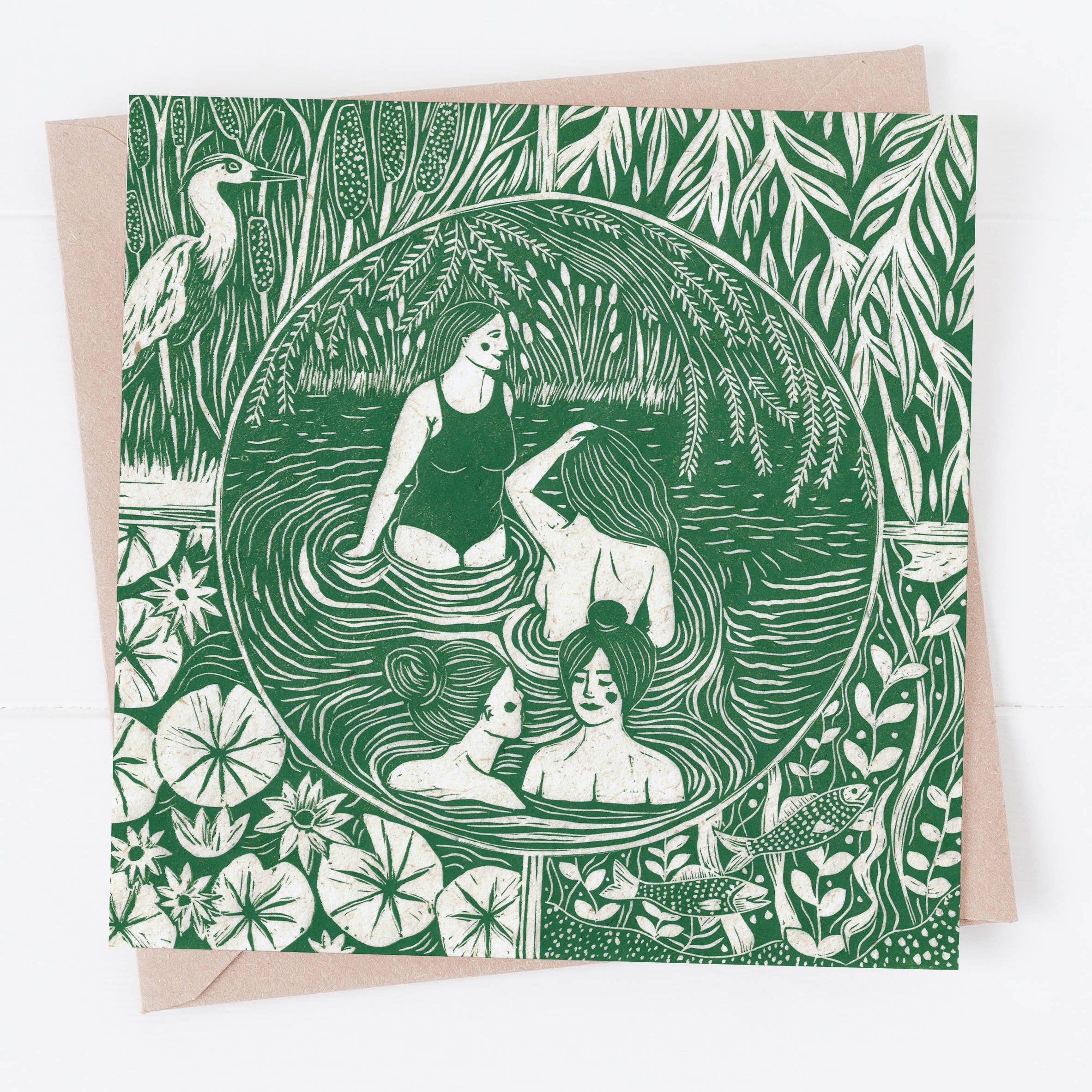 Greeting card with green and white illustration of women in a pond surrounded by nature on a beige envelope.