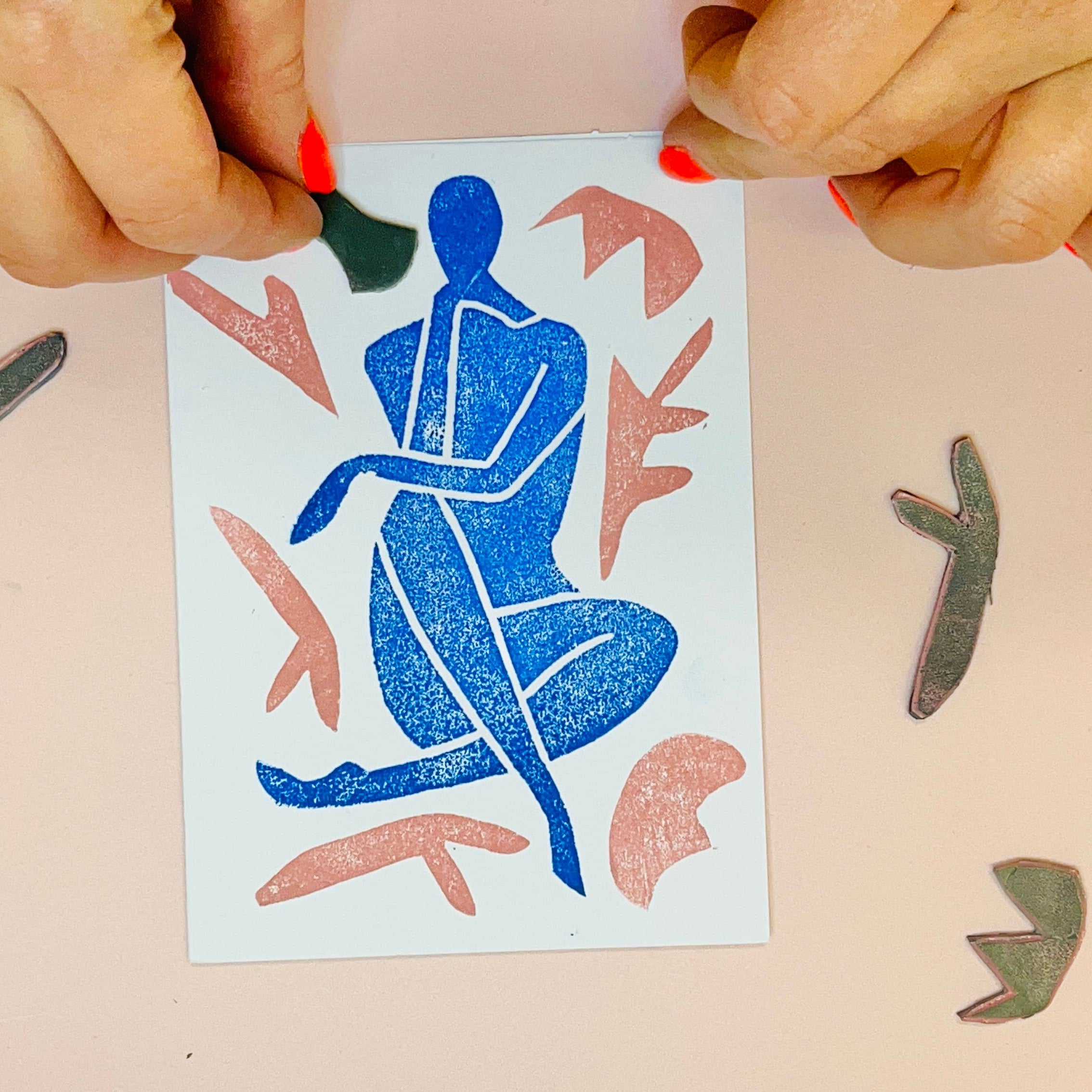 Person arranging cut-out paper figures on a beige background