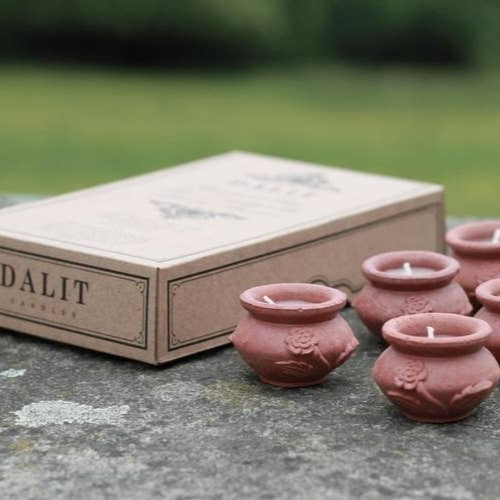 Set of small pink ceramic pots with candles next to a 'DALIT' branded box on a stone surface.