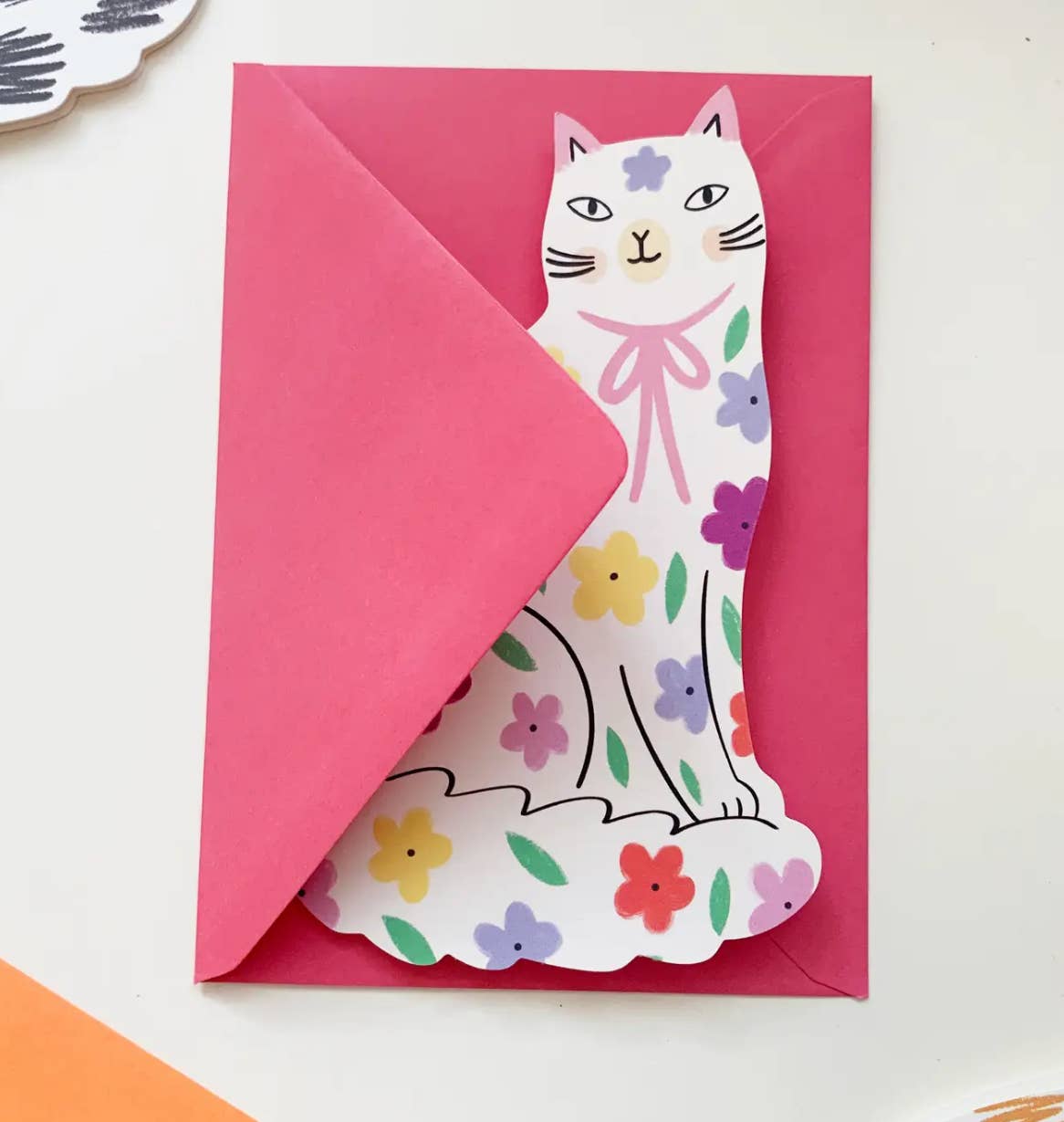 Card with a cat design on a pink envelope against a white background