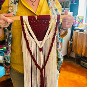 Woman holding a macramé wall hanging in a store setting
