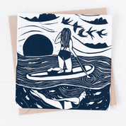 Greeting card with illustration of a person paddleboarding on a wave, surrounded by birds and mountains.