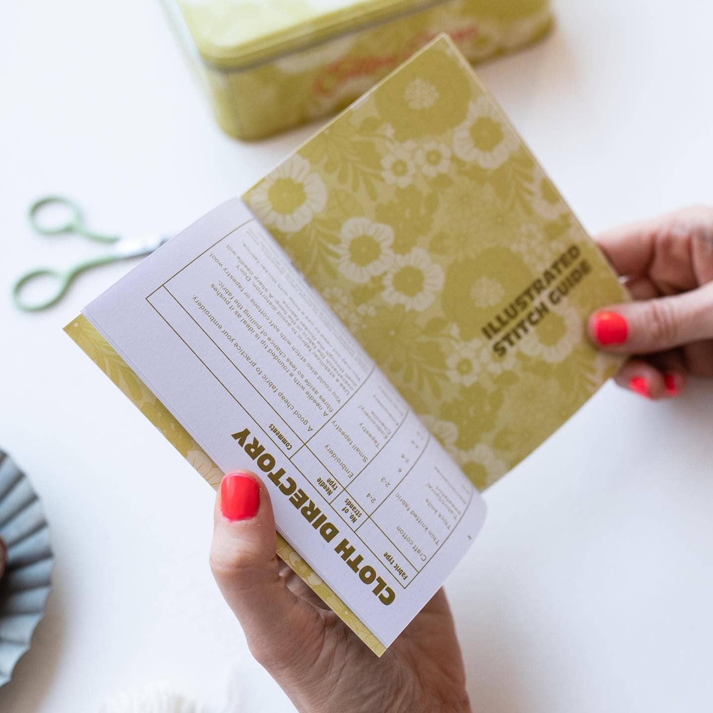 Hand holding a patterned book with text on a white background