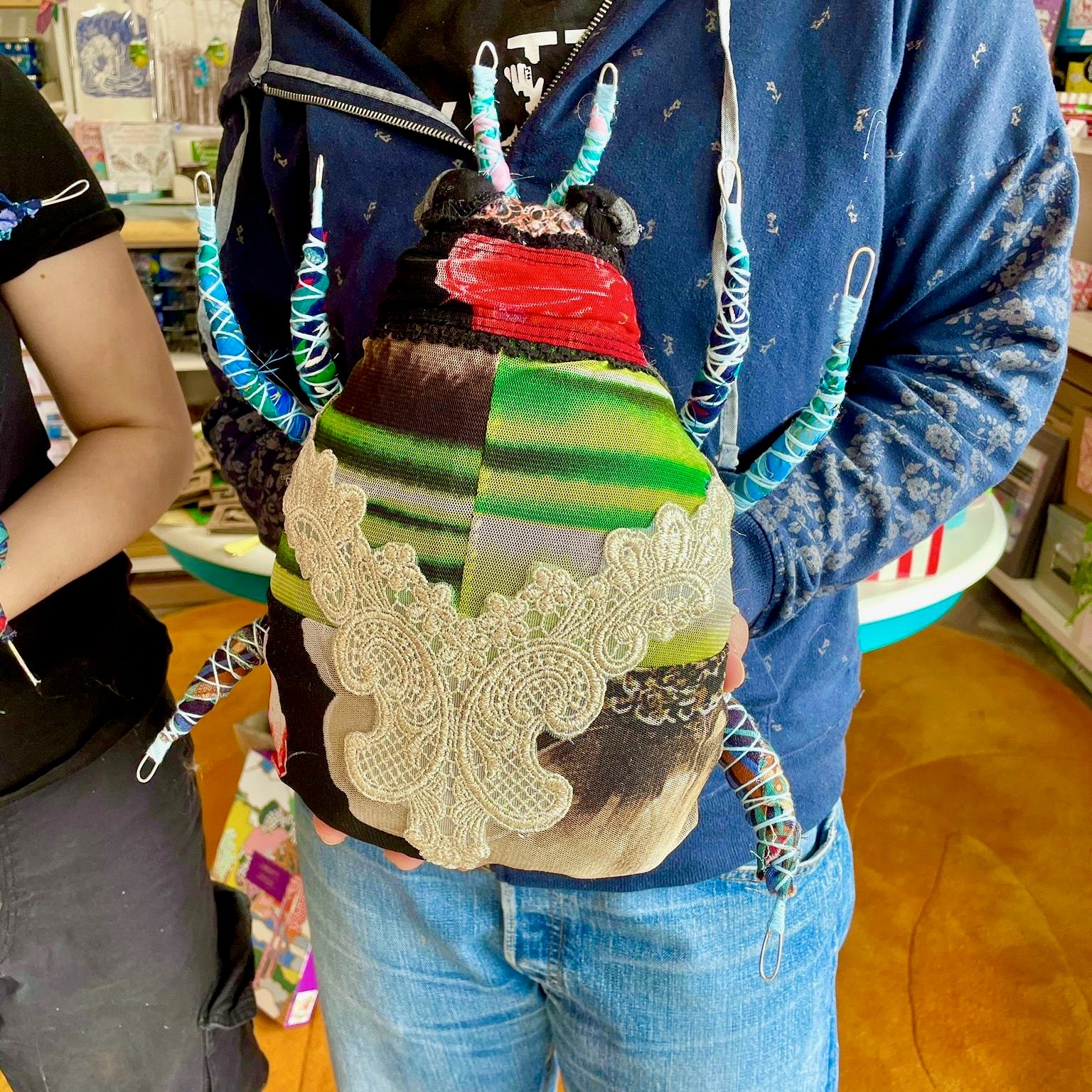 Person holding a colorful bag with decorative elements in an indoor setting
