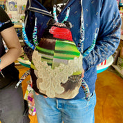 Person holding a colorful bag with decorative elements in an indoor setting