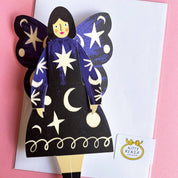Butterfly-shaped paper doll with star and moon designs on a pink background