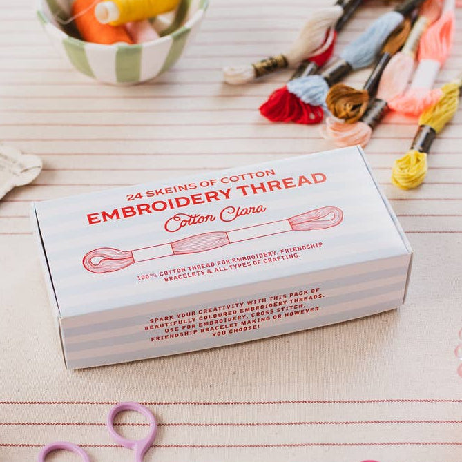 Box of embroidery thread with spools and scissors on a wooden surface