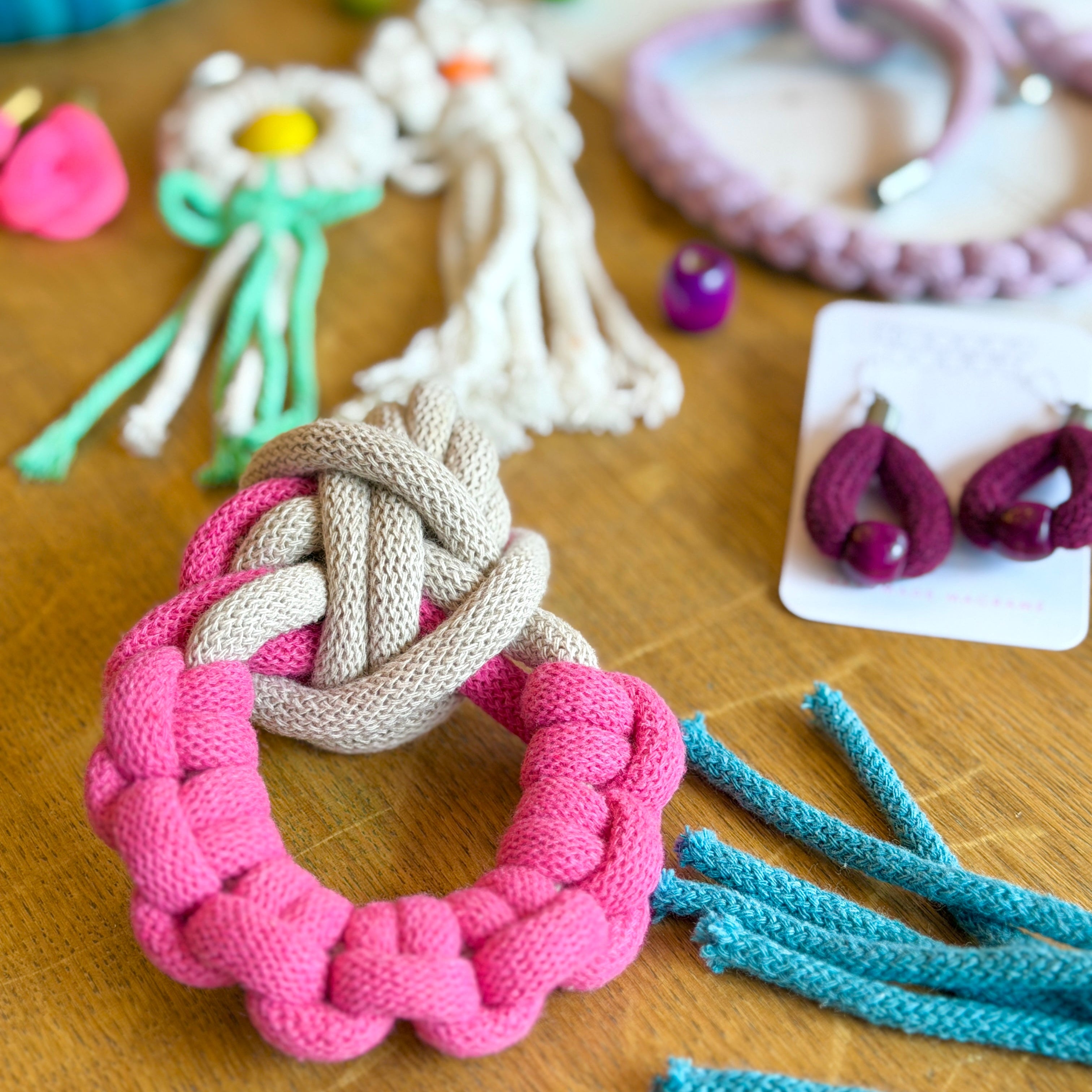 Pink and gray braided rope toy on a wooden surface with other toys in the background.