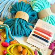 Colorful macrame yarn and tools on a wooden surface with 'Milana' branding.