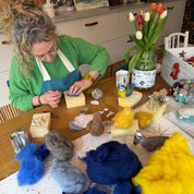 Person working with yarn and fibers on a table in a craft setting