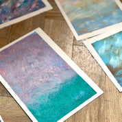 Colorful abstract paintings on paper scattered on a wooden surface