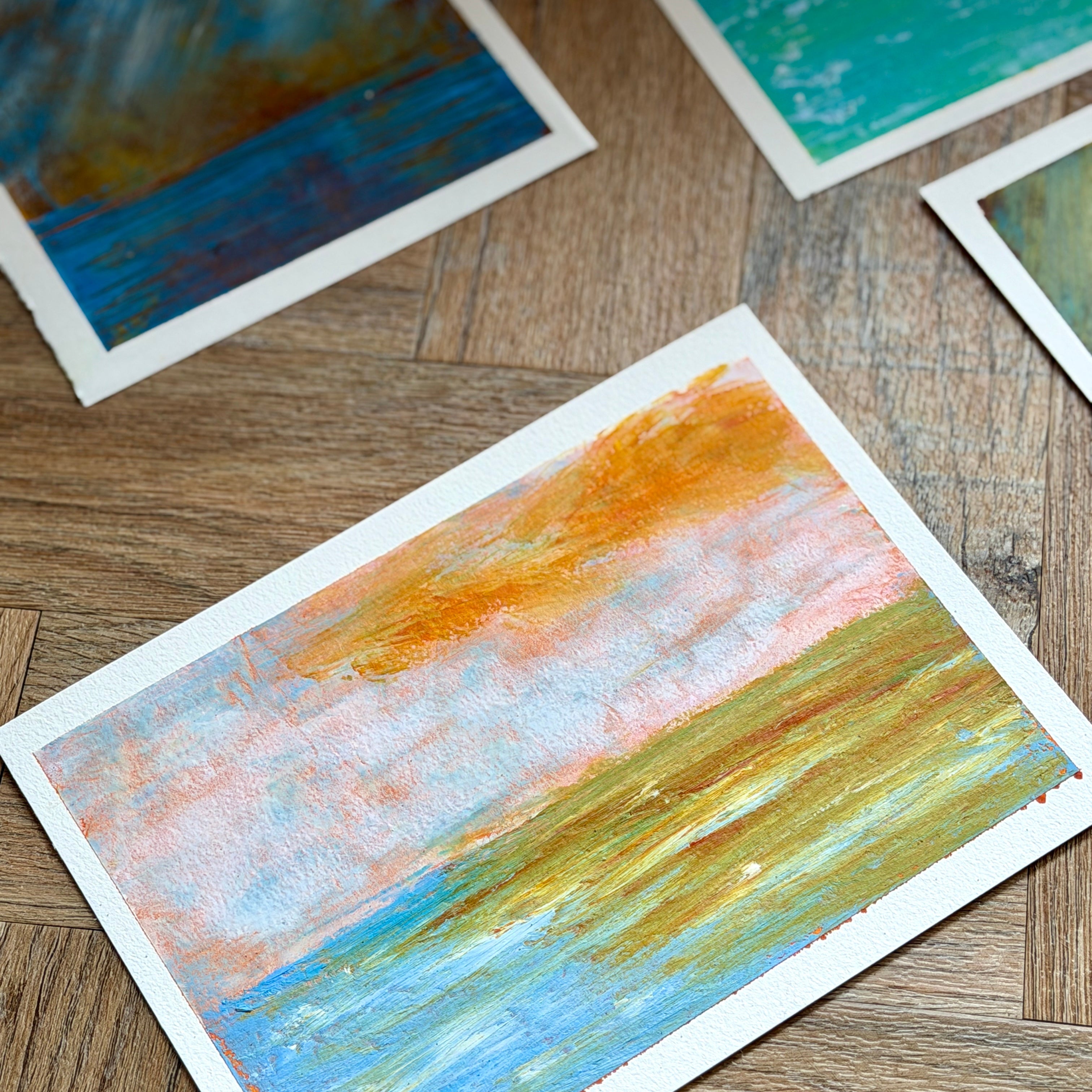 Four abstract art cards on a wooden surface