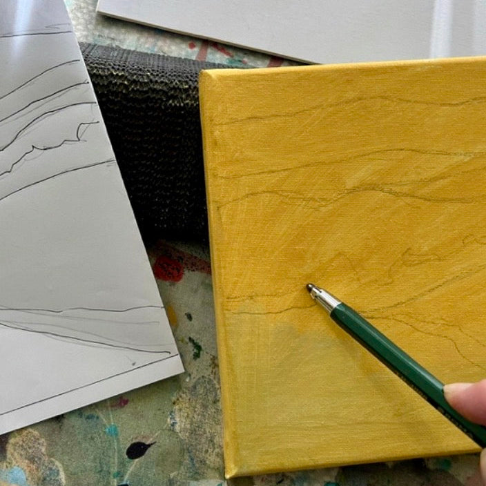 Hand holding a green pen over a yellow block with a white sheet of paper and black mesh in the background.