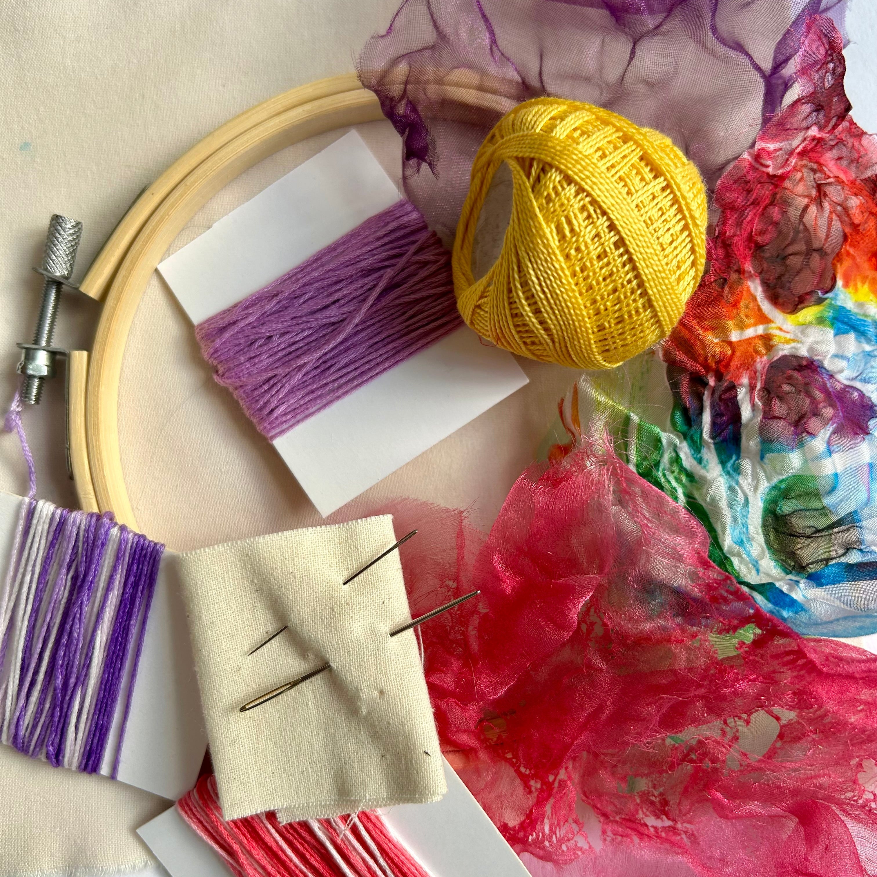Embroidery hoop with colorful threads and fabric on a light background