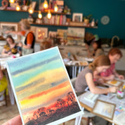 Person holding a colorful striped card with a blurred indoor background