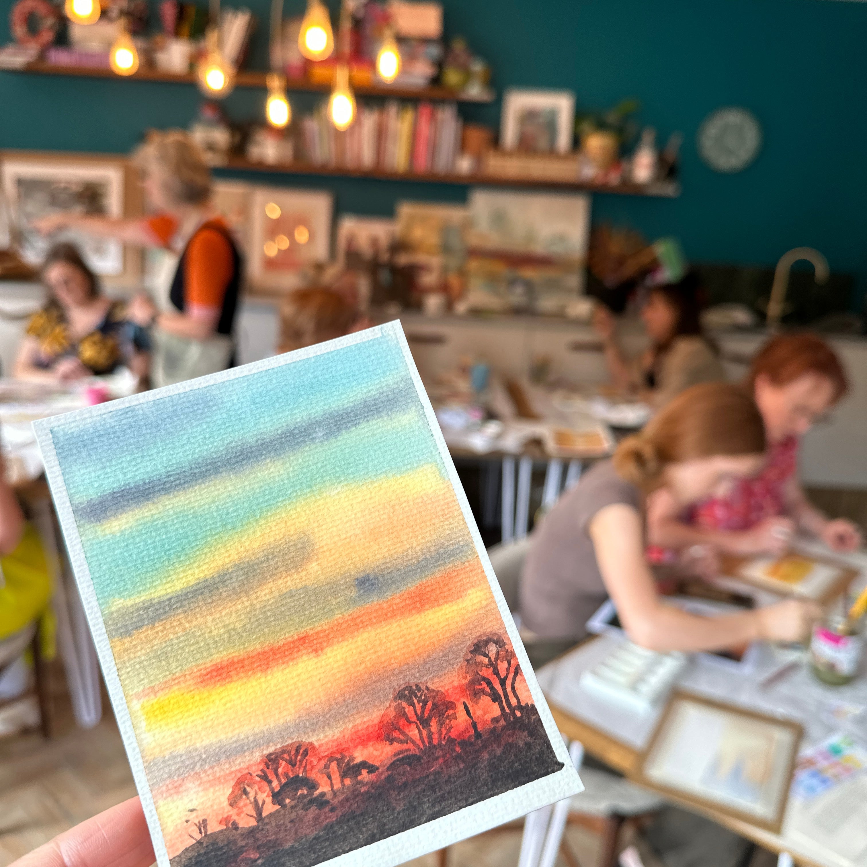 Person holding a colorful striped card with a blurred indoor background