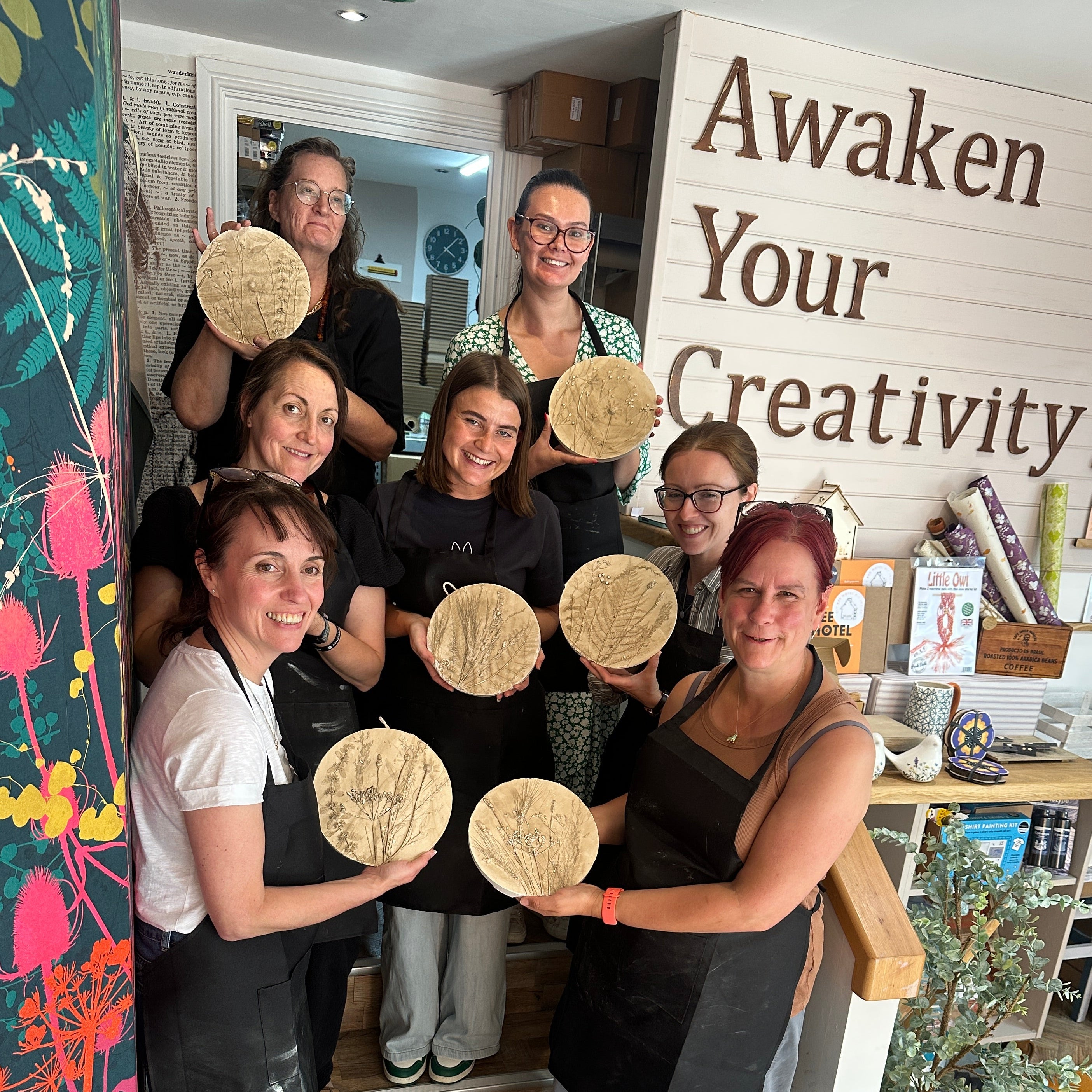 Group of people posing with bread in a room with a sign that says 'Awaken Your Creativity'.