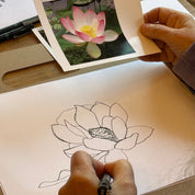 Person drawing a flower next to a photo of a pink flower