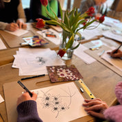 People drawing at a table with flowers in the center