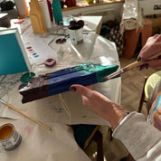 Person painting with a brush on a palette in an indoor setting