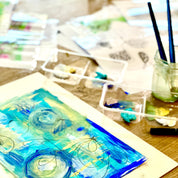 Artistic watercolor painting on paper with art supplies in the background