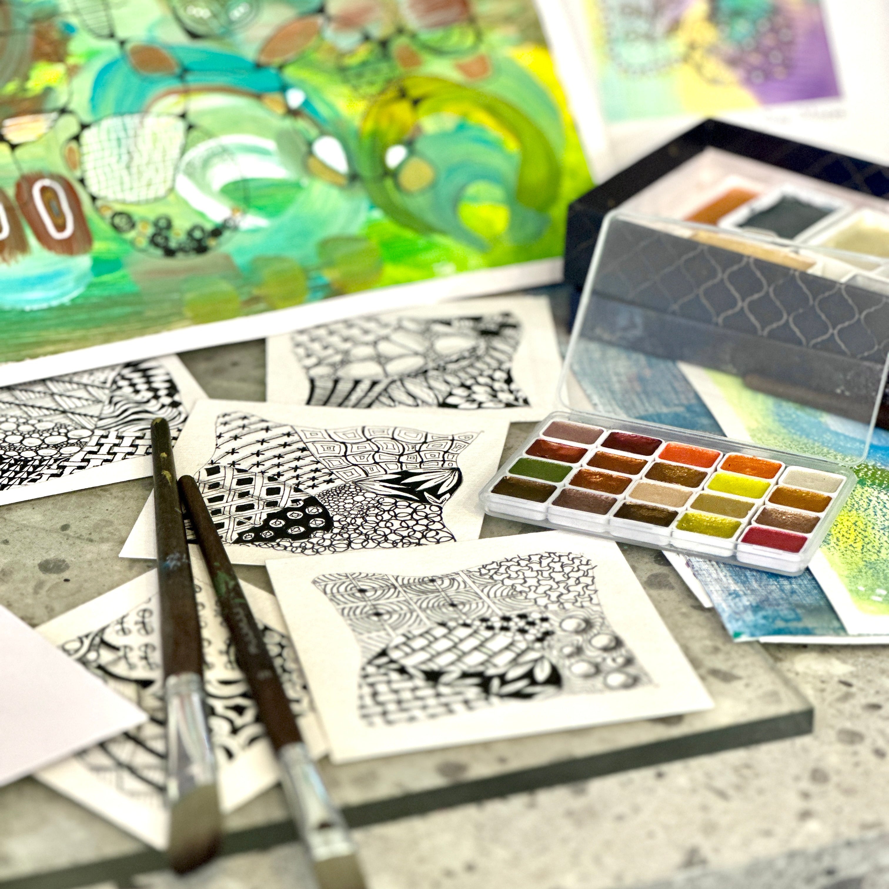 Art supplies including watercolor paints, brushes, and coloring books on a table.