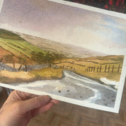 Hand holding a piece of paper with a topographic map design.