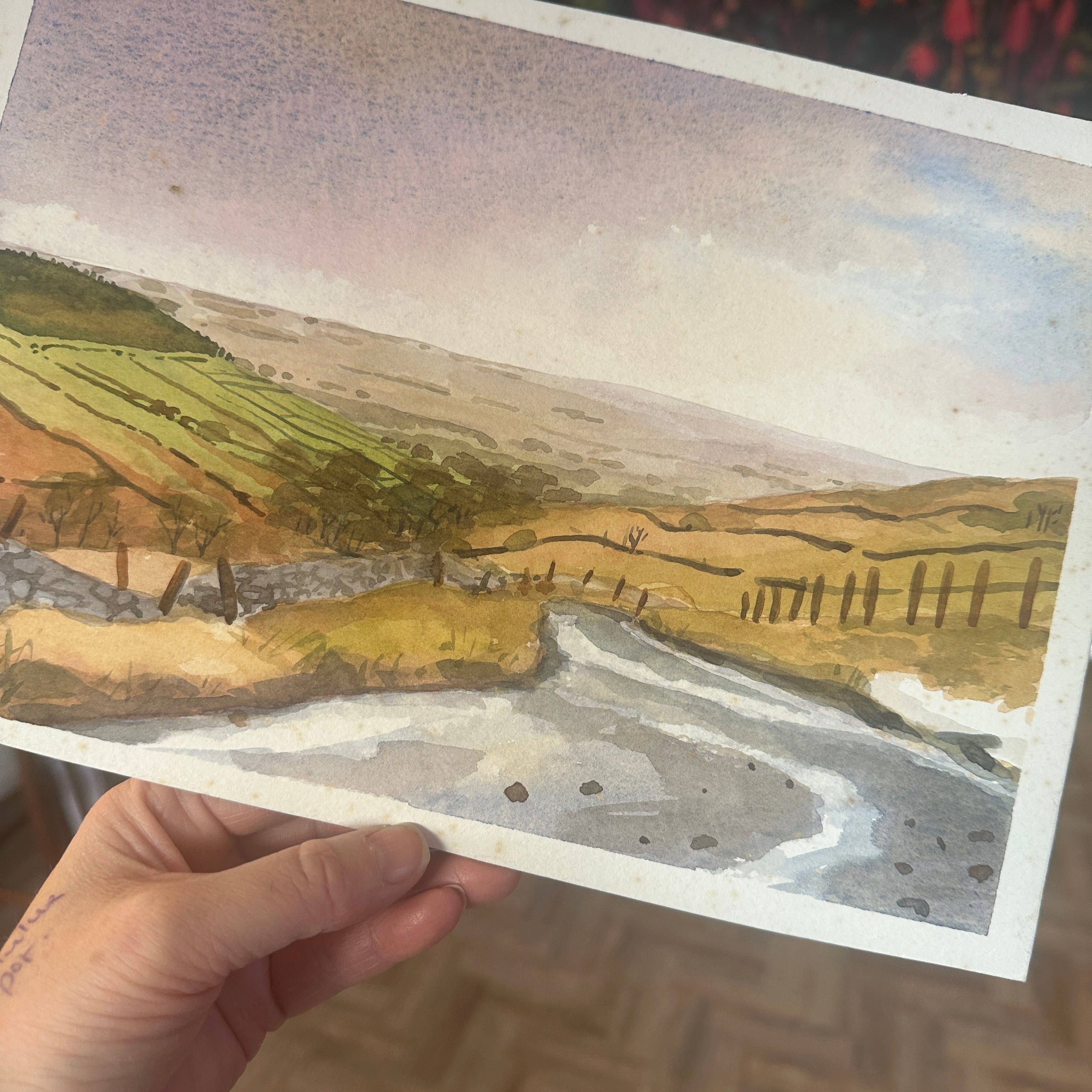 Hand holding a piece of paper with a topographic map design.