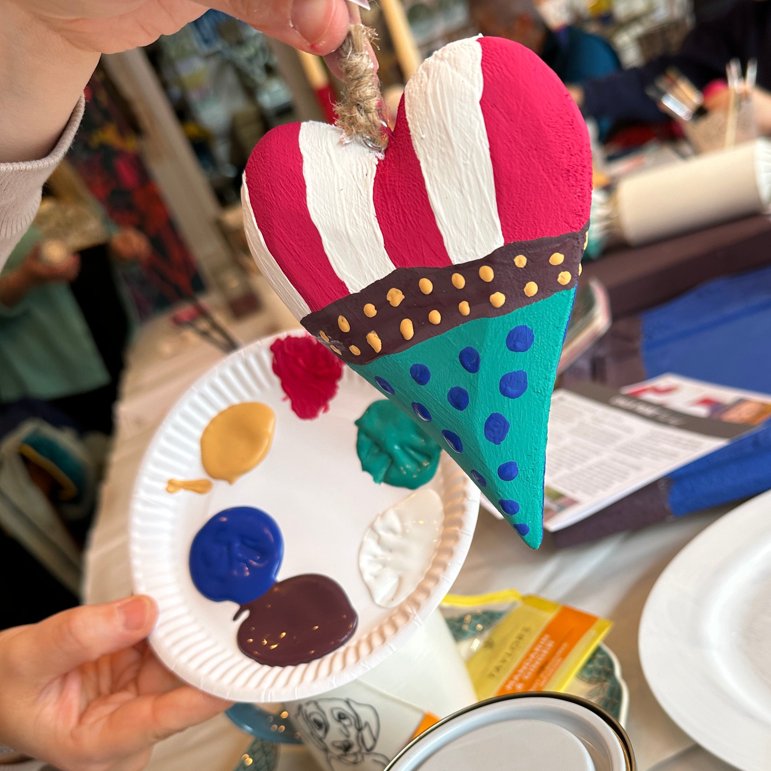 Artistic paper plate craft with colorful decorations and a can of paint.