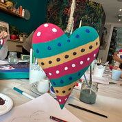 Colorful heart-shaped object on a cluttered desk with various items.