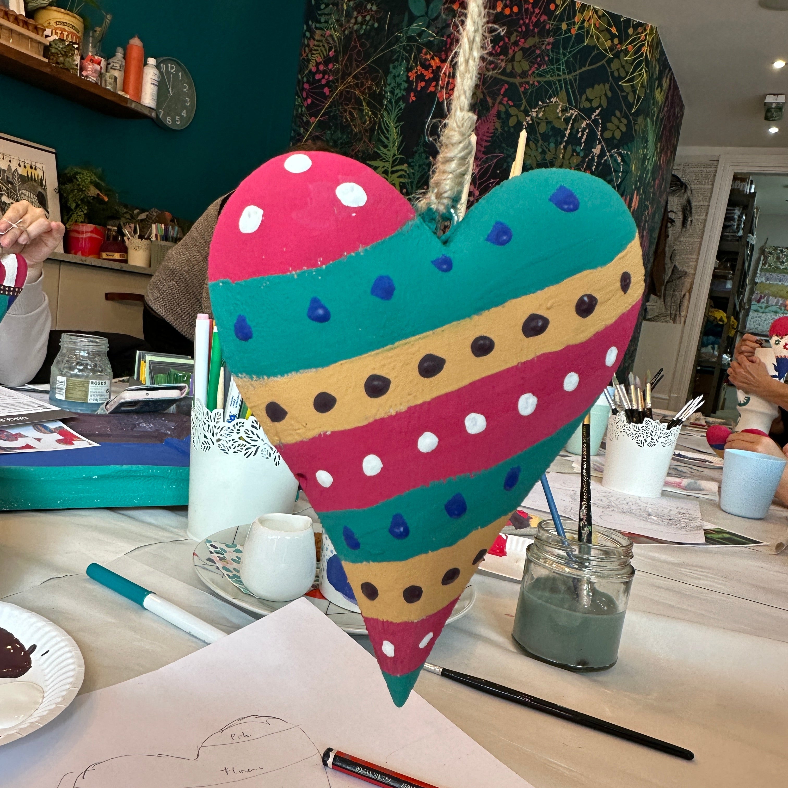 Colorful heart-shaped object on a cluttered desk with various items.