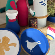 Decorative items including a blue disc with a white bird design, a red vase, and other colorful objects on a surface.