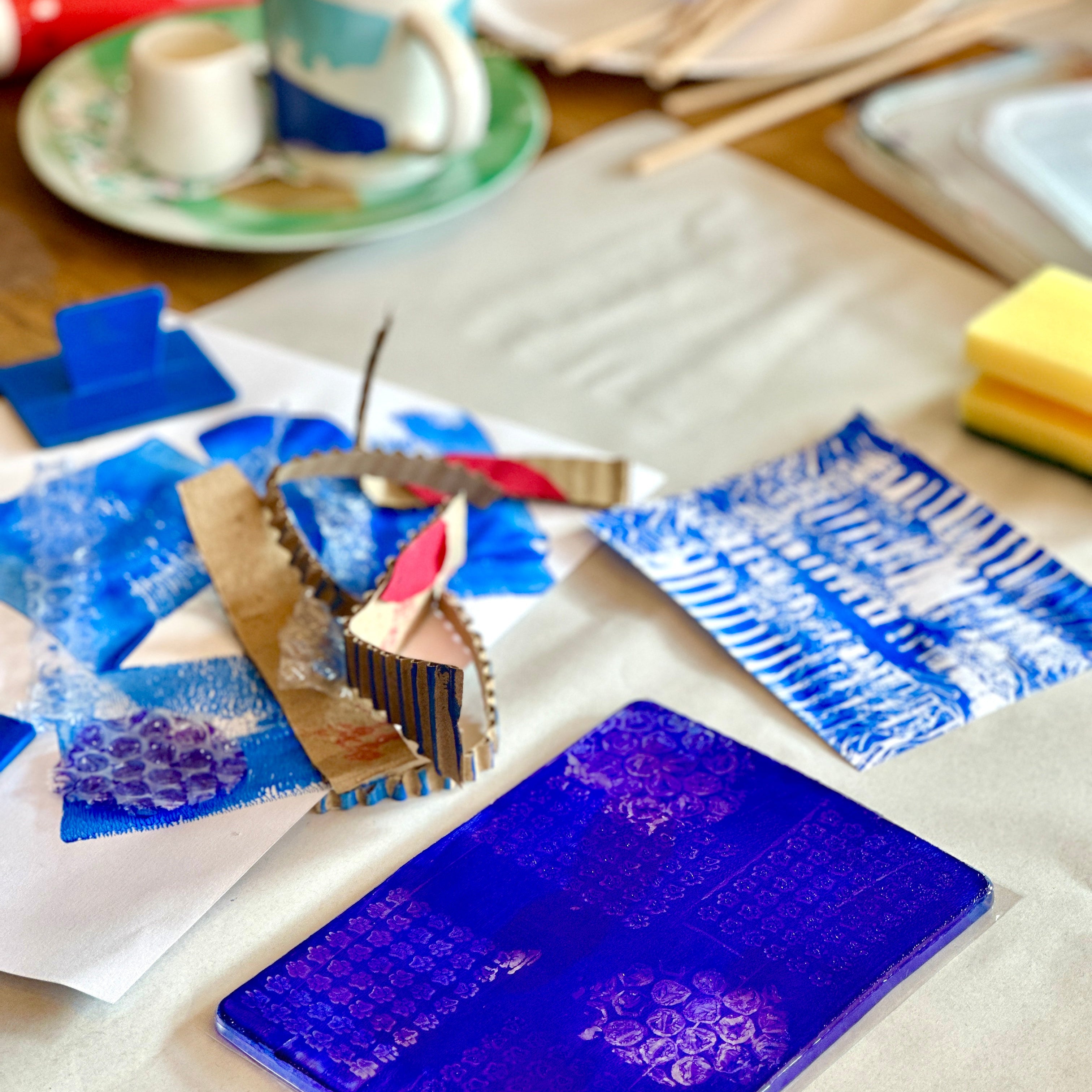 Blue textured art piece on a table with tools and materials