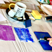 Table with various items including a mug, plates, and a phone on a checkered tablecloth.
