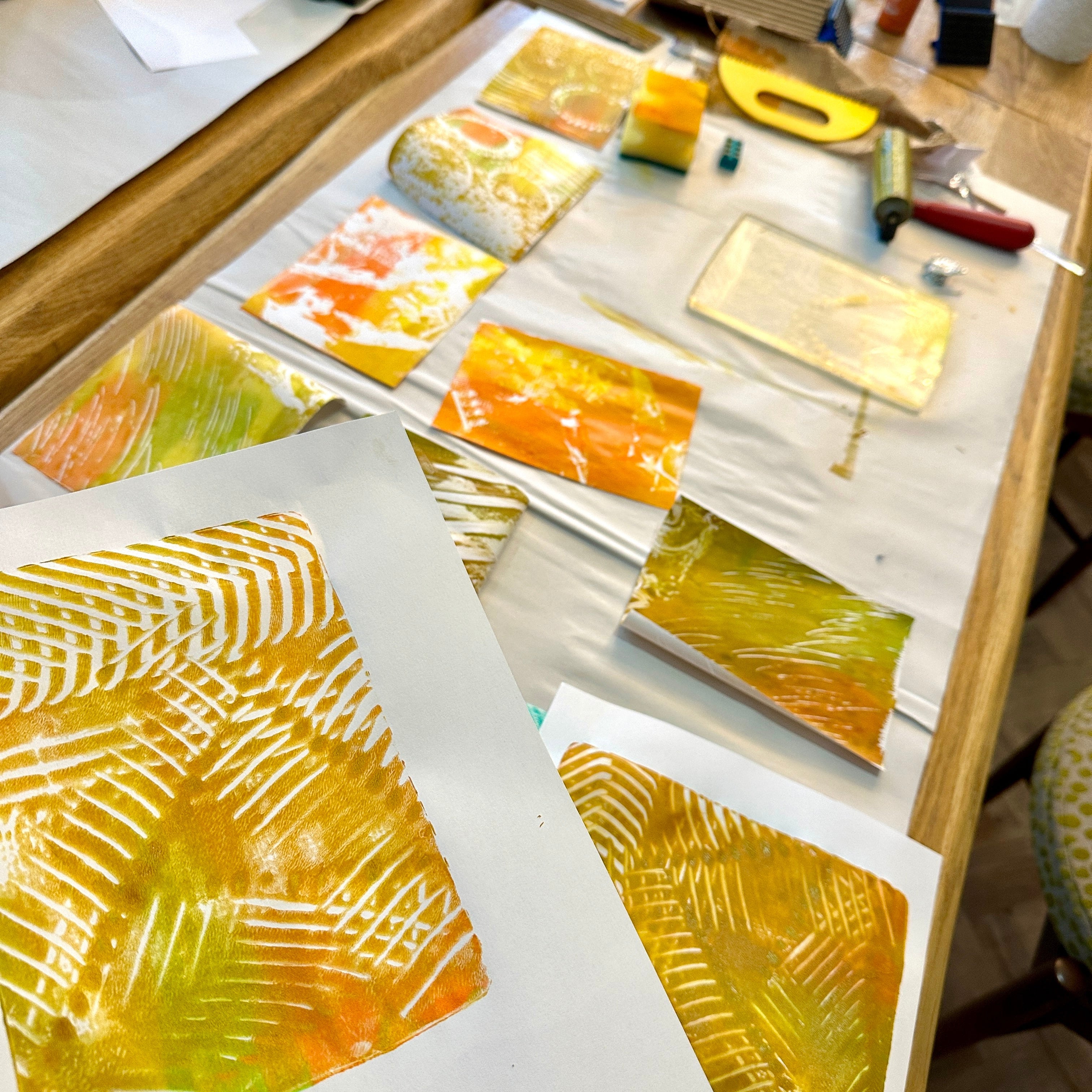Artistic printing process with inked plates and prints on a table.